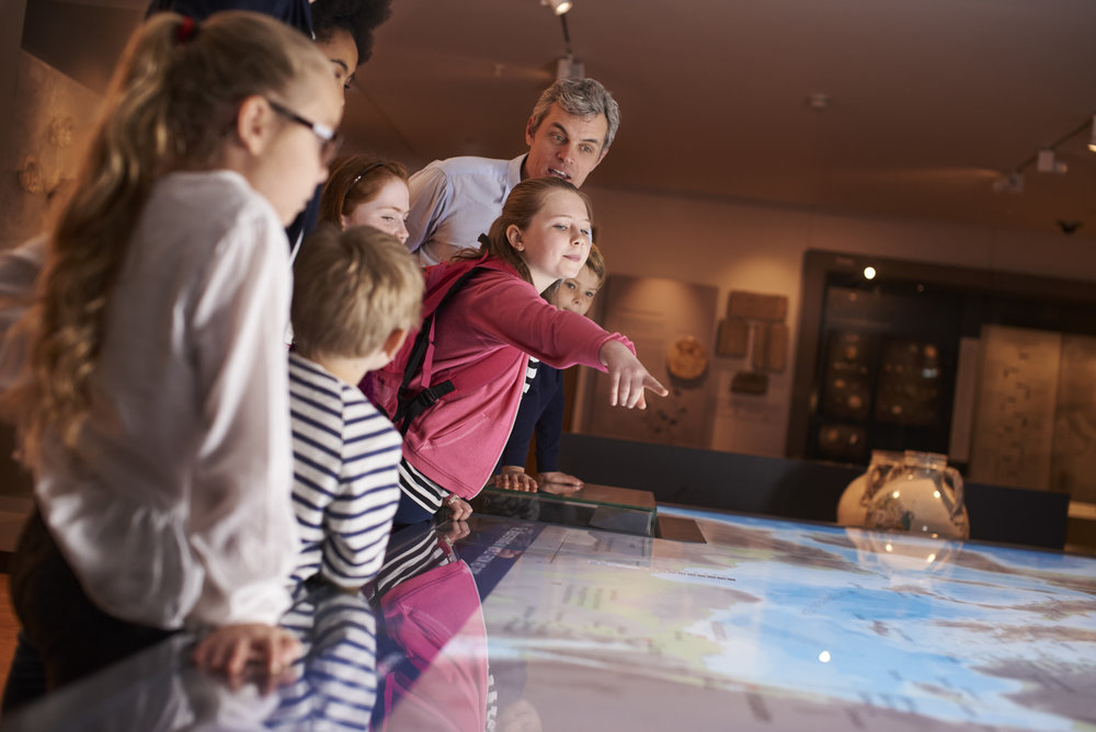 Pupils On School Field Trip To Museum Looking At Map